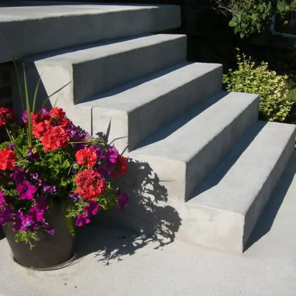 Finished concrete steps beside a planter of red and purple flowers